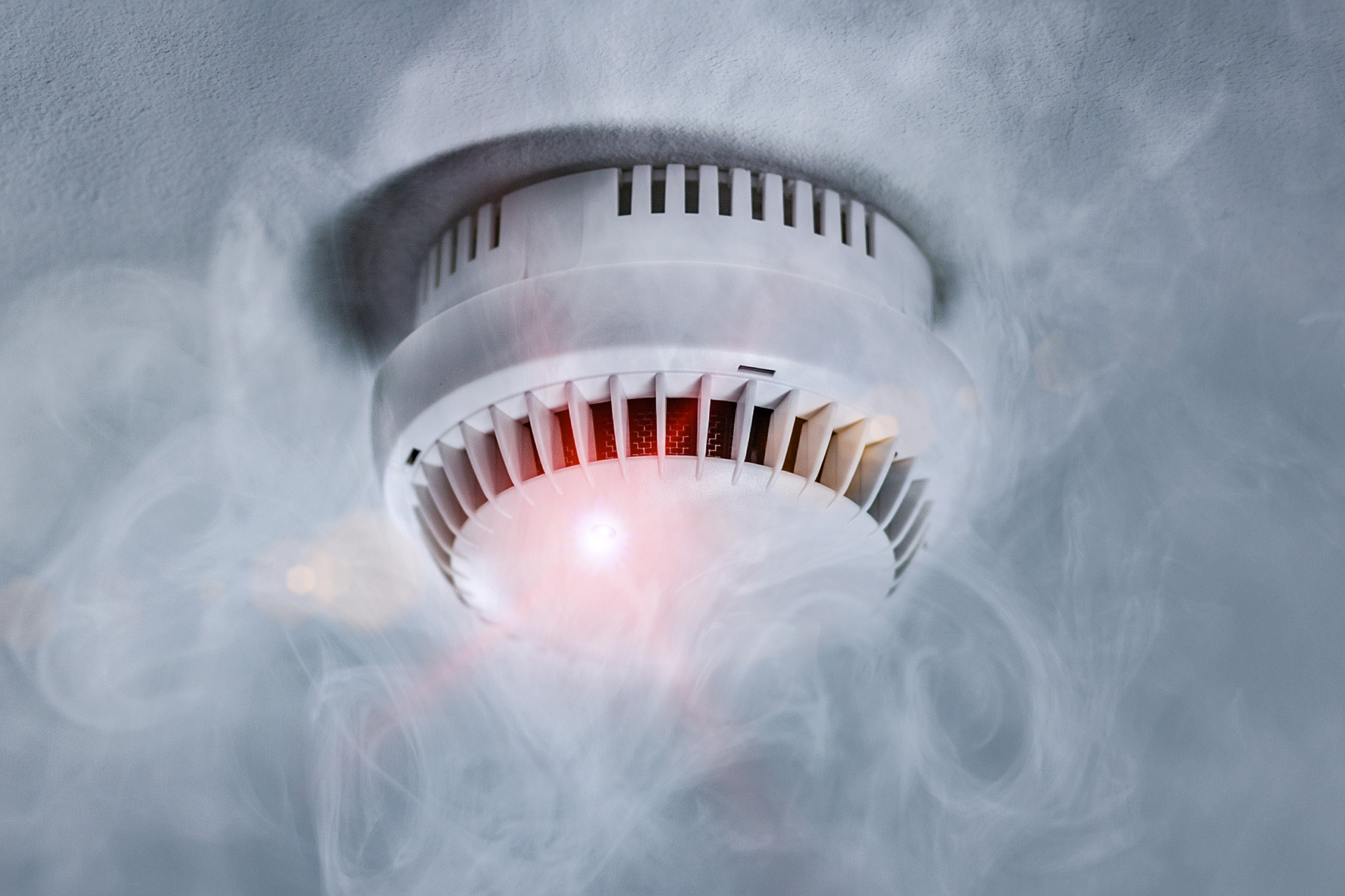Smoke detector on ceiling surrounded by smoke